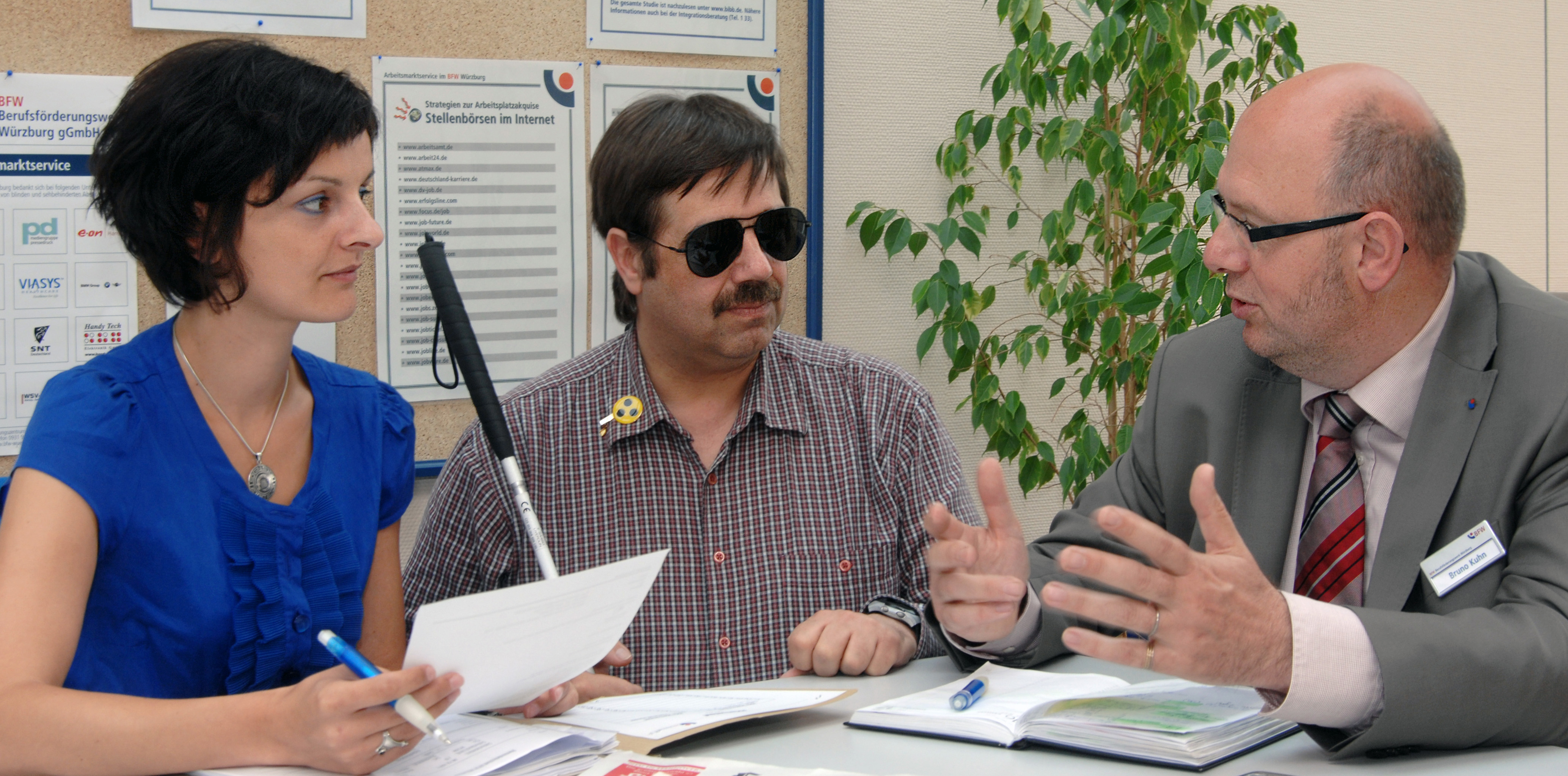 Foto blinder Teilnehmer im Gespräch mit zwei Case-Managern
