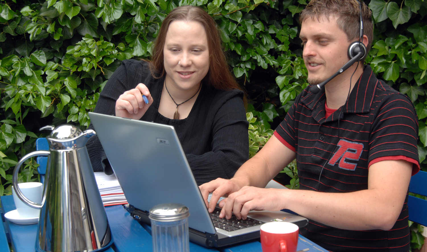 Foto einer jungen Frau und eines jungen Mannnes beim eLearning im Freien